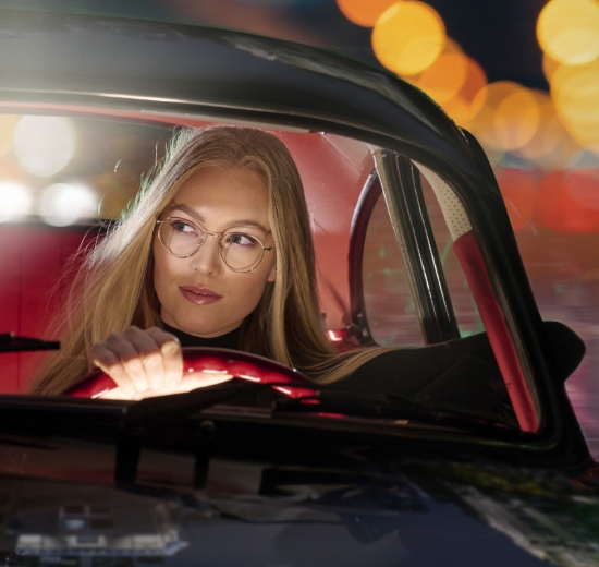 Frau mit Brille am Steuer bei Nacht. 